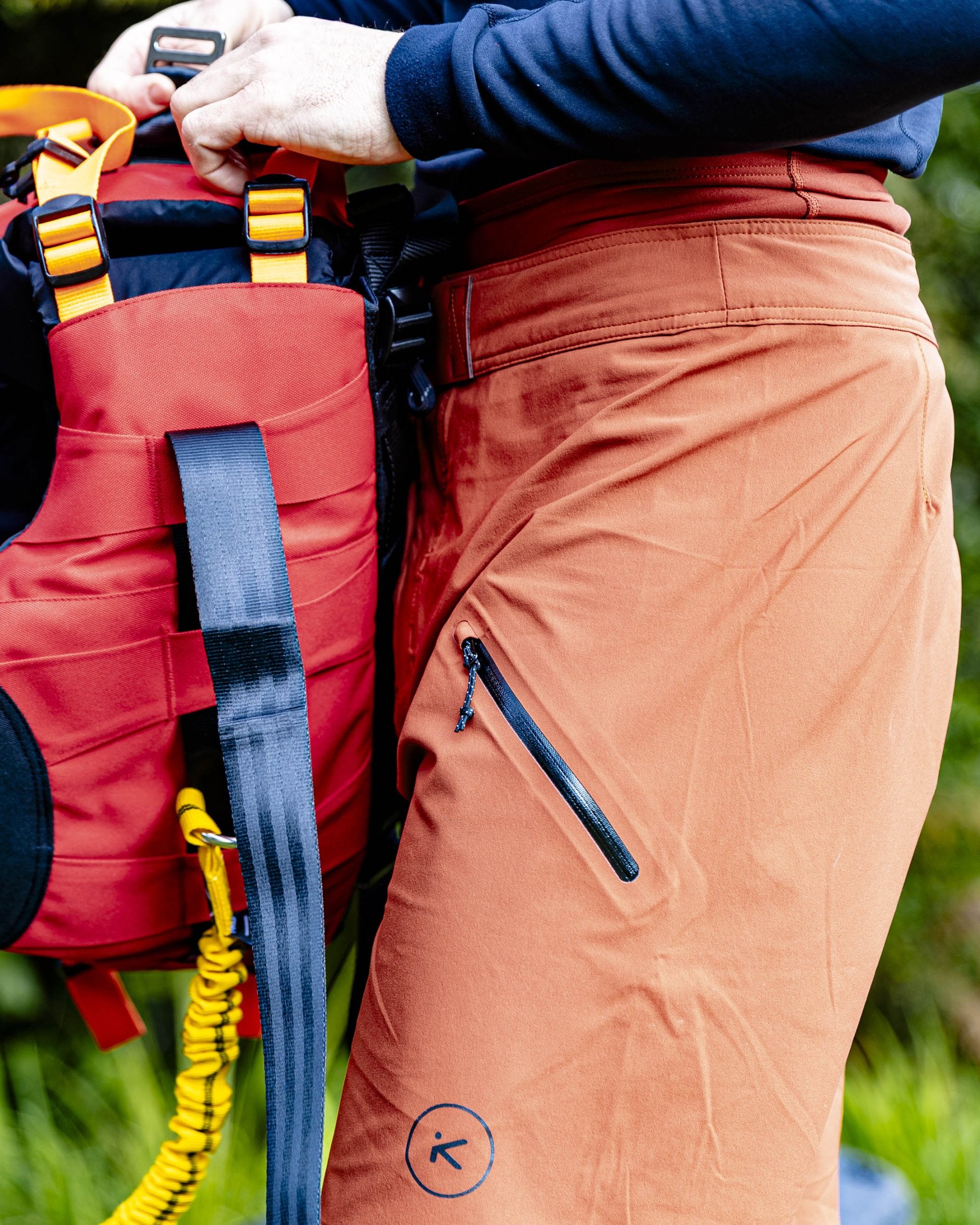 Person wearing orange pants with a red backpack outdoors