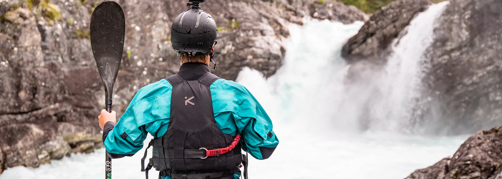 Back view of paddler standing looking at whitewater wearing Hiko PFD 